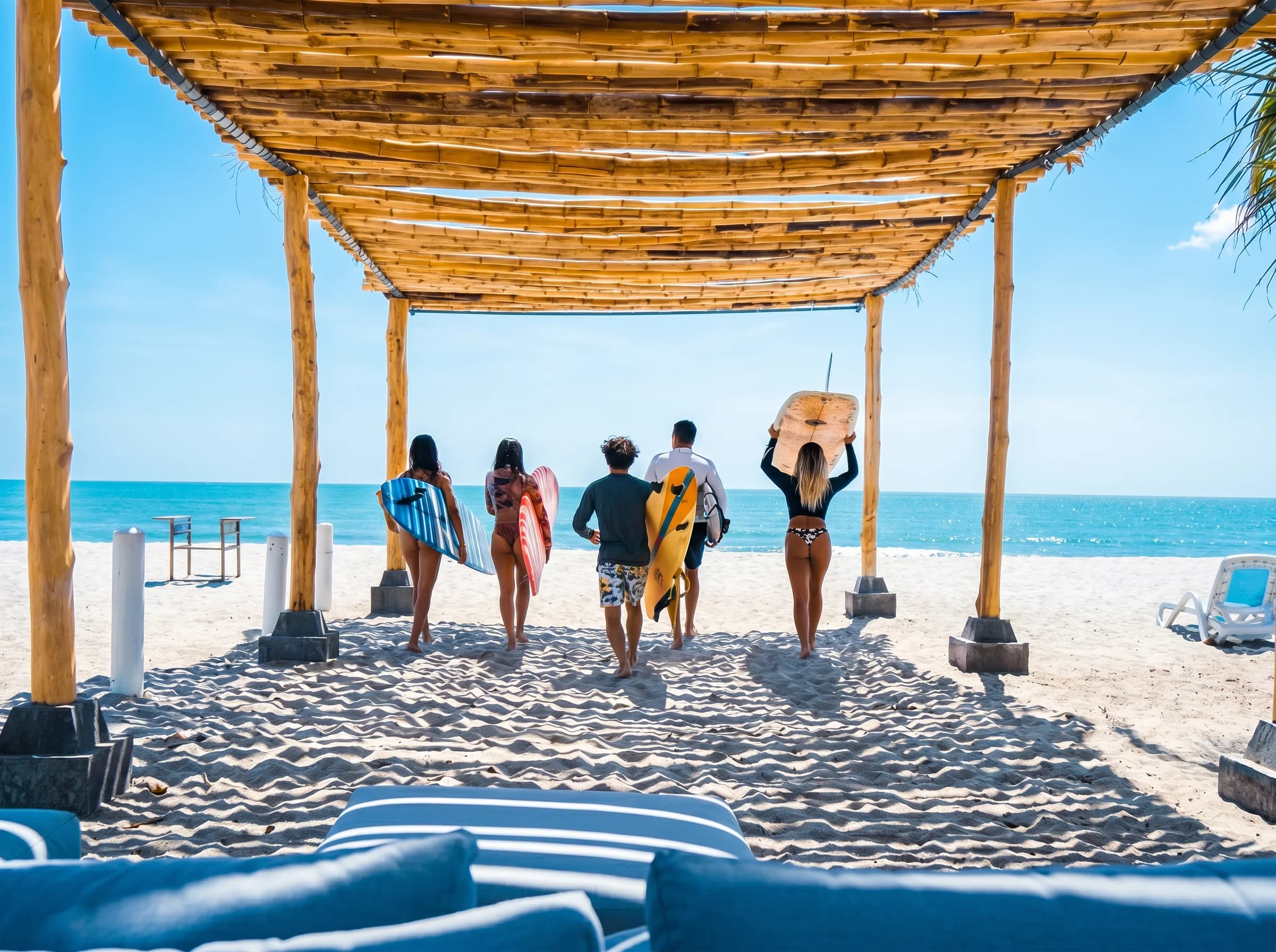 A group of friends carrying surfboards toward the sea at Playa Caracol