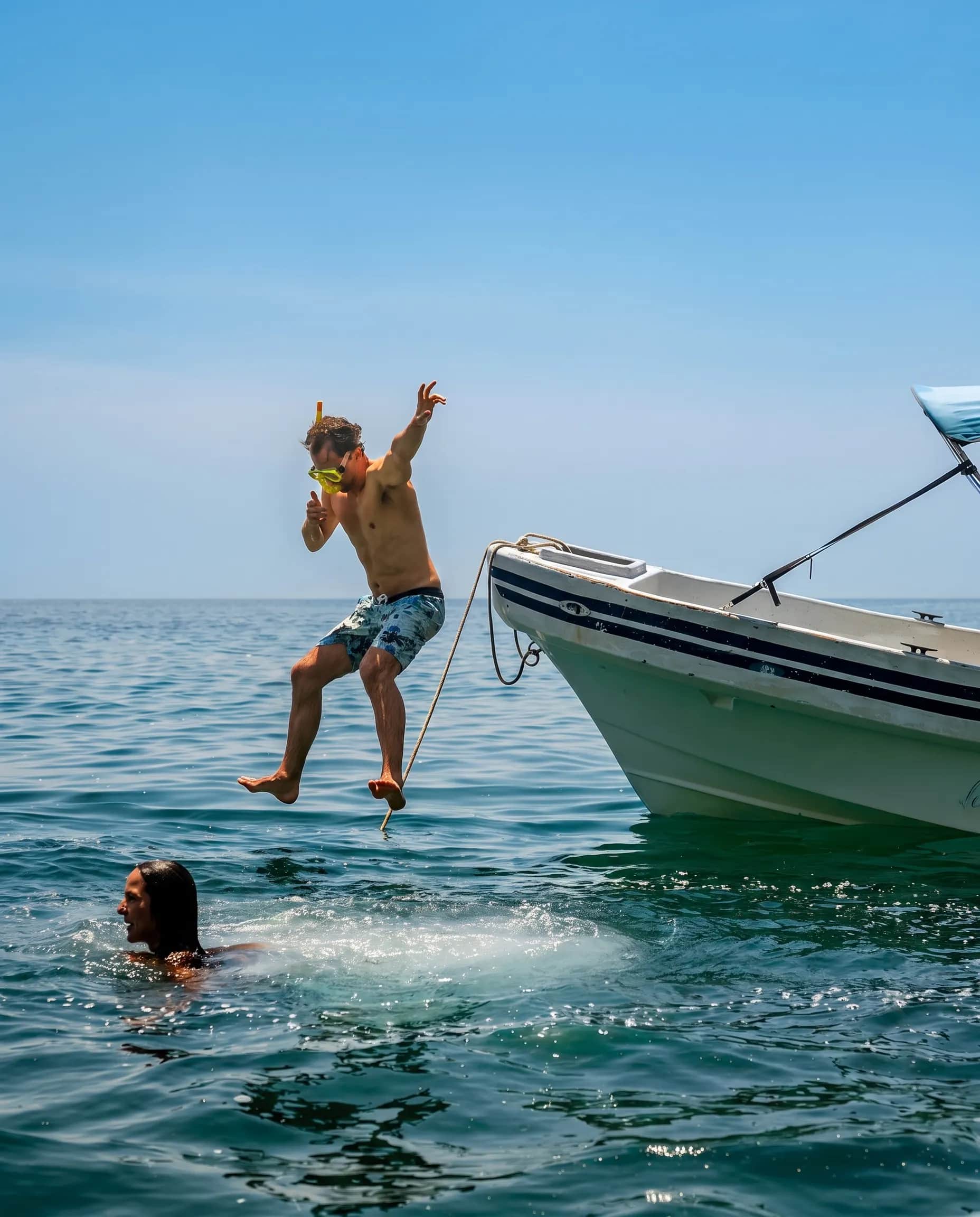 Kid jumping into the sea from a boat
